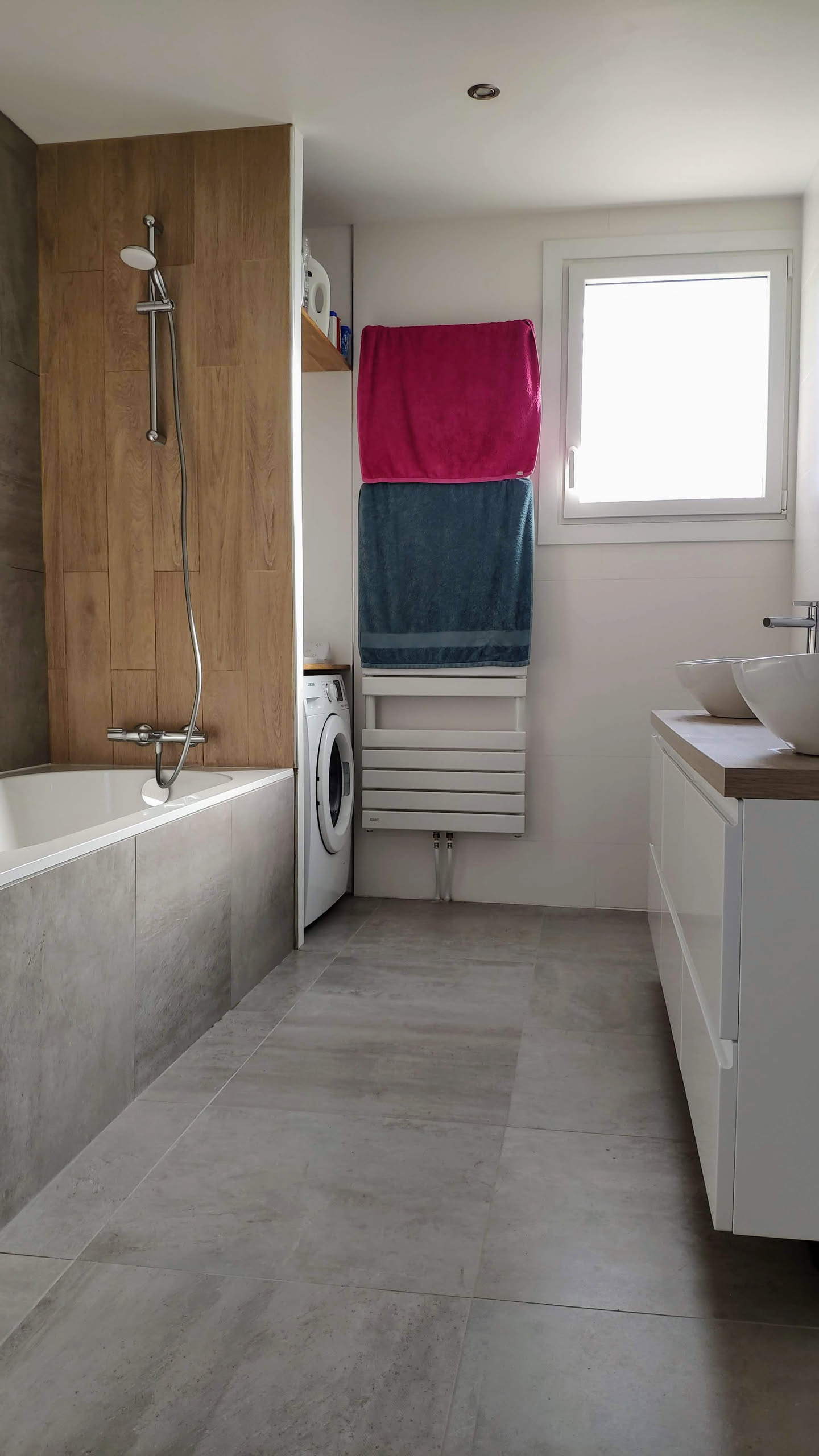 Vue de la salle de bain terminée avec baignoire, carreaux à effet bois et sèche-serviettes