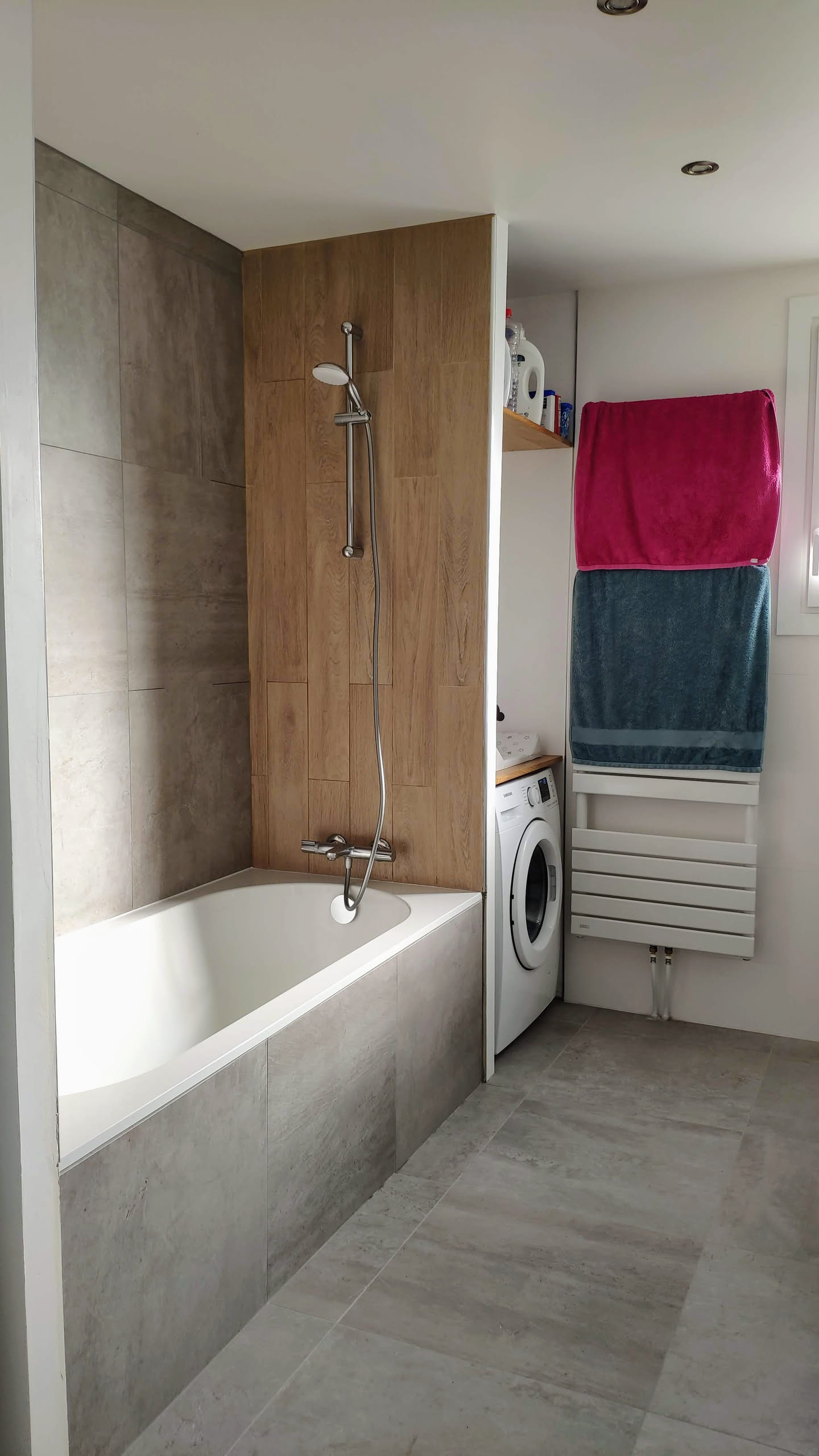 Vue d'ensemble de la salle de bain avec fenêtre, sèche-serviettes et plan de travail du meuble vasque